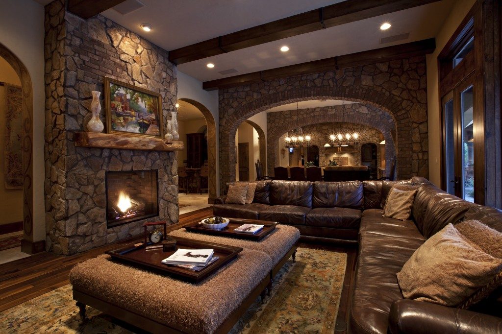 Большой кожаный угловой диван в тон с каминным порталом: готовое решение для больших неразделённых апартаментов